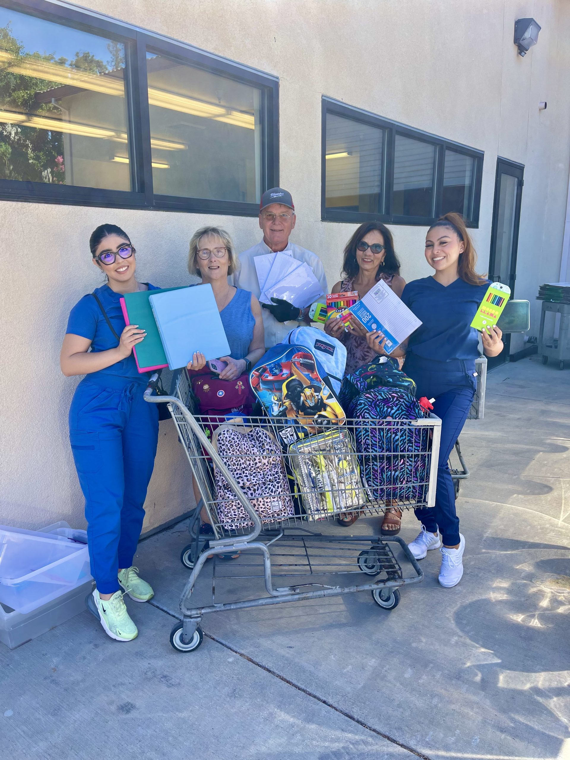 Trosien staff standing behind a shopping cart filled with backpacks